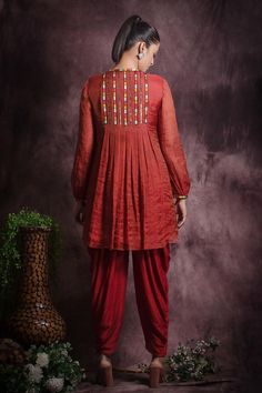 Brick red closed neck A line front pleated top with scattered metallic embellishments and gathered hem. Paired with dhoti pant.
Components: 2
Pattern: Embroidery
Type Of Work: Sequin, Beads, Thread Work
Neckline: Closed Round Neck
Sleeve Type: Full Flounced Sleeves
Fabric: Silk tissue , Viscose silk and Lining: Cotton
Color: Red
Other Details: 
Multicolour thread embroidery at neck and sleeve hem
Length:
Kurta(in inches): 33        
  Dhoti(in inches): 37


Occasion: Sangeet, Mehendi and Haldi - Dhoti Pants, Pant For Women, Pleated Top, Pleat Top, Pattern Embroidery, Thread Embroidery, Fabric Silk, Thread Work, Red Silk