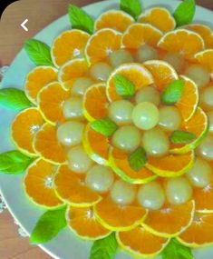 a plate with oranges and green leaves on it that is made to look like a flower