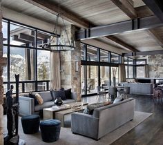 a living room filled with lots of furniture next to a stone wall covered in windows