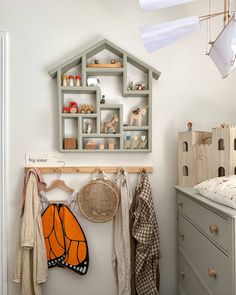 a baby's room with clothes and toys hanging on the wall next to a dresser