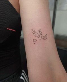 a woman's arm with a small dove tattoo on the left side of her arm