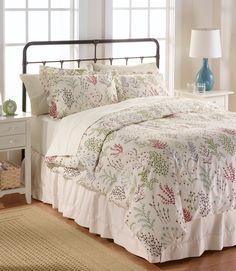 a bed in a bedroom with white sheets and pillows on top of the bedspread