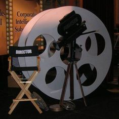 an old movie projector sitting in front of a large white film reel on a tripod