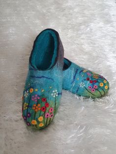 a pair of blue slippers with flowers painted on them sitting on a white furnishing