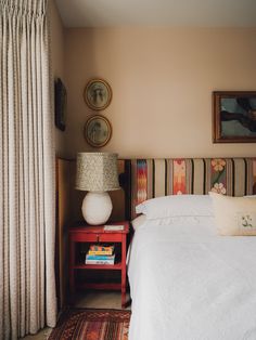 a bed sitting next to a window with curtains on both sides and a table in front of it