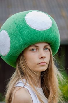 a girl wearing a green mushroom hat with white dots on it's face and long blonde hair