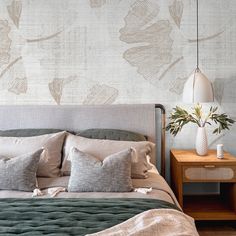 a bed with pillows and blankets on top of it in front of a wallpapered background