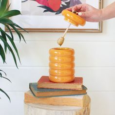 a person is holding a honey dipper over some books