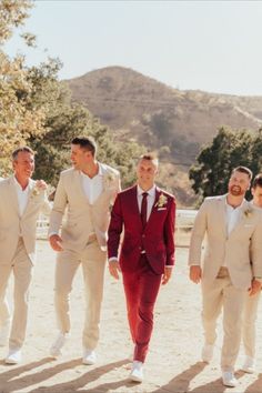 three men in suits are walking down the street together and one man is wearing a red suit