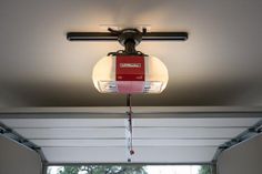 a red and white light hanging from the ceiling in front of an open garage door