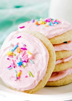 a stack of sugar cookies with pink frosting and sprinkles on top