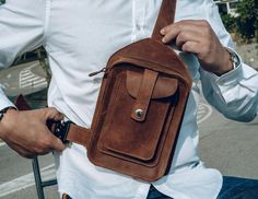 a man is holding a brown leather bag