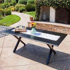 a table with flowers on it sitting in the middle of a yard next to a brick wall