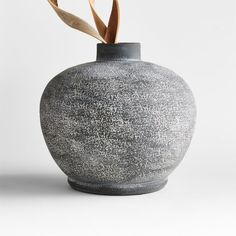 a gray vase with a plant sticking out of it