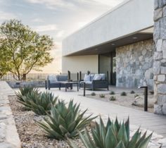 an outdoor patio with chairs and plants next to it