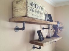 an old wooden crate is mounted on the wall above two shelves with metal pipe holders