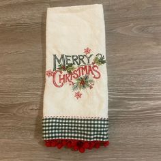 a white towel with merry christmas written on it and pom - poms around the edges