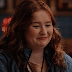 a close up of a person wearing a necklace and looking at the camera with a smile on her face