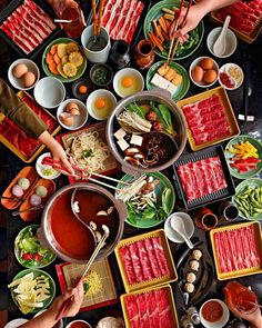 a table topped with lots of food and chopsticks on top of it's sides