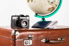 an old suitcase with a camera and a globe on top