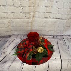 a red glass plate with some christmas decorations on it and a candle in the center