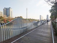 a person walking on a bridge over a body of water with tall buildings in the background