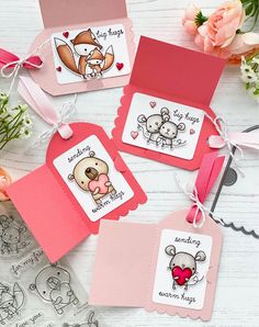 three tags with animals on them are sitting next to some flowers and pink ribbones