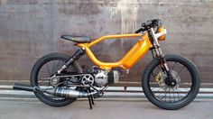 an orange motorcycle parked next to a wall