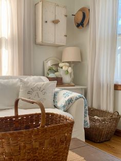 a wicker basket sitting on top of a white couch in a living room next to a window