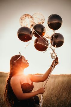 a woman is holding balloons in the air