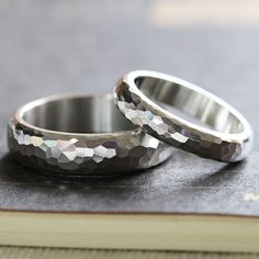 two silver wedding rings sitting on top of a book next to each other with hexagonal patterns