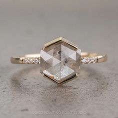 an engagement ring with a hexagon cut diamond and pave diamonds on the side