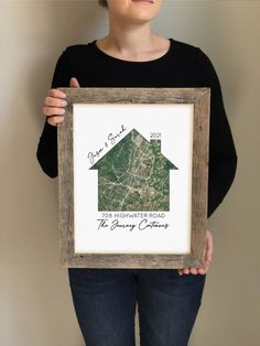 a woman holding up a framed photo with the words our home is located on it