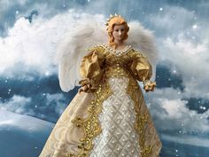 an angel doll with white wings and gold trim standing in front of a cloudy sky