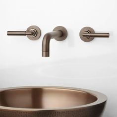 a copper sink with two faucets on the wall and one in the bowl