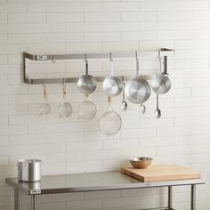 pots and pans are hanging on the wall above a table with a cutting board