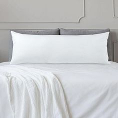 a bed with white sheets and pillows on it