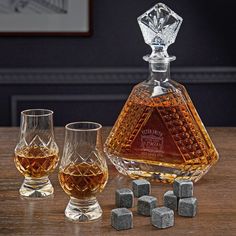 a bottle of whiskey sitting on top of a wooden table next to glasses and ice cubes