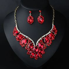 a red necklace and earring set on a black mannequin neckpiece with matching earrings