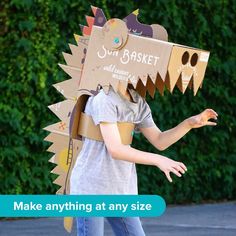 a young boy wearing a cardboard dinosaur costume