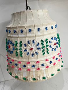 a white lamp with blue, red and green beads hanging from it's side