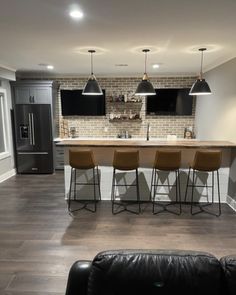 a living room filled with furniture next to a brick wall and an open kitchen area