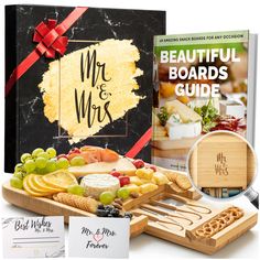 a wooden tray with cheese, fruit and crackers on it next to a book