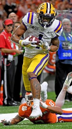 a football player running with the ball in his hand and people watching from the sidelines