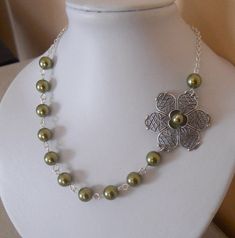 A delicate, sophisticated, elegant look to this stunning necklace.  Flowers, flowers, flowers...this necklace is a cascade of flowers. A beautiful Silver plated flower been adorned with a silver plated flower and a  olivine glass pearl. This special cascade of flowers is continued with 8 mm olivine pearls.  I used silver plated chain for this necklace and it is 18'' long with a 2'' extender.  Please email me if you need this necklace in a different size or different color of pearls (info@handcraftedjewelryart.com)  You will get the necklace in a beautiful gift box. Elegant Silver Flower Necklace With Decoration, Elegant Silver Flower Decoration Necklace, Elegant Green Flower Pendant Necklaces, Elegant Green Flower Pendant Necklace, Elegant Pearl Chain Flower Necklace, Elegant Flower Necklace With Pearl Chain, Elegant Flower-shaped Pearl Chain Necklace, Green Flower Pendant Jewelry For Wedding, Elegant Pearl Chain Flower Necklace As Gift