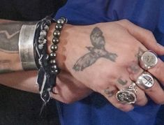 a person with tattoos and rings on their hands