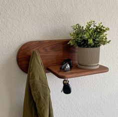 a potted plant sitting on top of a wooden shelf next to a coat rack