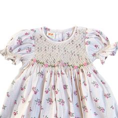 This lovely dress features a cream-colored fabric adorned with delicate pink and purple flowers. The smocked detailing adds a charming touch to the overall design, making it a perfect choice for a stylish and elegant look.  * 100% Cotton * 2 layers * Handmade * Tie at the back * Lightweight, soft cotton, comfortable * Hand wash or machine wash on a delicate setting We are based in Sydney, New South Wales, Australia. Within Australia, Standard shipping is $7 flat rate via AusPost. There is option Fitted Feminine Floral Dress With Smocked Back, Feminine Fitted Floral Dress With Smocked Back, Spring Floral Dress With Smocked Back, Spring Fitted Smocked Dress With Ditsy Floral Print, Pink Floral Summer Dress With Smocked Bodice, Fitted Smocked Dress With Ditsy Floral Print For Spring, Pink Floral Dress With Smocked Back For Garden Party, Spring Cotton Dress With Smocked Back, Feminine Smocked Dress With Puff Sleeves For Garden Party