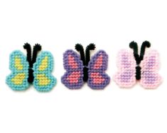 three small cross stitch butterfly brooches in different colors and sizes, one is black, one is pink, one is blue