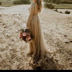 a woman standing in the sand holding a bouquet